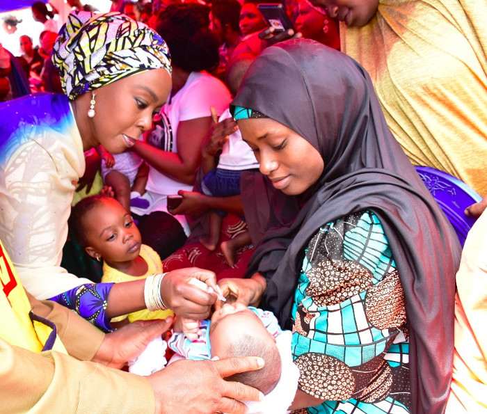 Mrs Toyin Saraki administering oral polio vaccine on a child